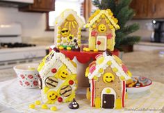 three decorated gingerbread houses sitting on top of a kitchen counter next to a christmas tree