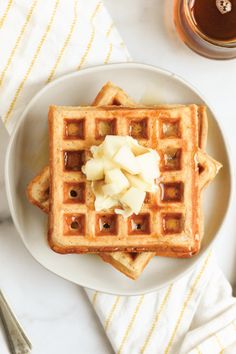 waffles with butter and syrup on a plate next to a cup of coffee