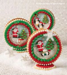 three decorated christmas ornaments sitting on top of a white table covered with snowflakes