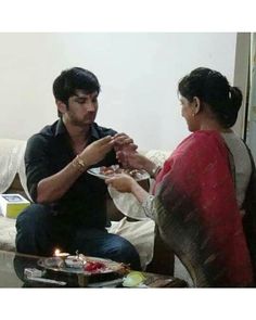 a man and woman sitting on a couch eating food from plates in front of each other