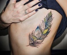 a woman's stomach with a feather tattoo on the side of her belly and hand