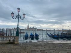 several gondolas are tied to poles in the water near a light pole and street lamp