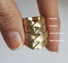 a woman's hand holding a gold ring with four different bands on it and the names of each band