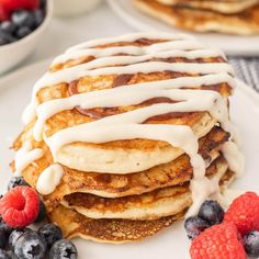 a stack of pancakes covered in icing and berries