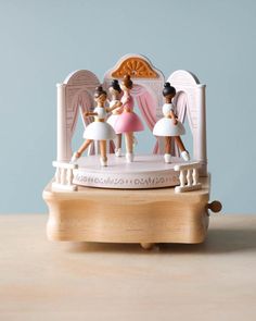 a small figurine is on top of a wooden stand with an angel and ballerinas