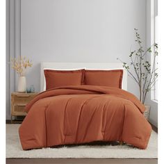 a bed with an orange comforter and pillows