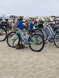 many bicycles are parked on the sand at the beach