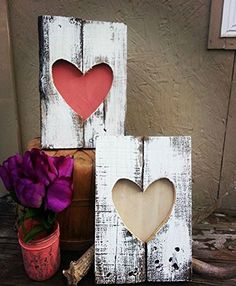 two wooden hearts sitting on top of a table next to a vase with flowers in it