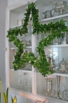 an old china cabinet is decorated with greenery