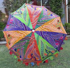 a colorful umbrella sitting on top of a lush green field in front of a house