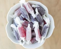 a white bowl filled with assorted candy on top of a wooden table