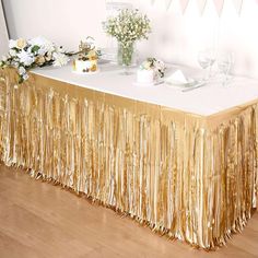 the table is covered with gold tinsel and has flowers in vases on it