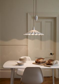 a white table topped with plates and bowls next to a light hanging from the ceiling