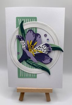 a white card with purple and yellow flowers on it, sitting on a wooden easel