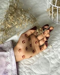 a woman's hand with hendix on it and flowers in the background