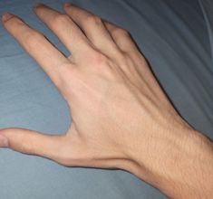 a person's hand resting on top of a bed