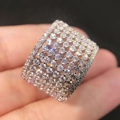 a hand holding a ring with diamonds on it's sides and in the middle