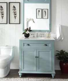 a bathroom vanity with a blue cabinet and mirror on it's side, next to a toilet