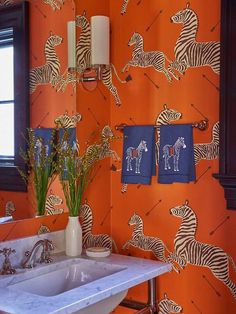 an orange bathroom with zebras on the wall and blue towels hanging from the towel rack