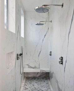 a walk in shower sitting under a window next to a tiled floor and white walls