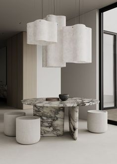 a marble table surrounded by white stools and lamps