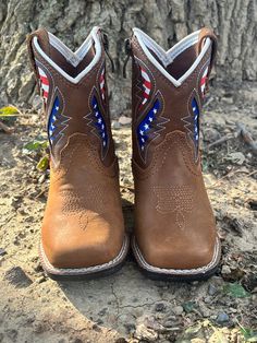 Dress ‘em up in style with these Ariat LIL’ STOMPERS boot by M&F Western Products. Genuine leather vamp. Shaft has pierced overlay with USA flag, stars and stripes underlay. Leather boot pulls and side zip closure. Comfortable, durable and fashionable. Brown Toddler Sizes: 04-07 Pierced Overlay USA Flag, Stars and Stripes Underlay Leather Boot Pulls Side Zipper Western Store, Boot Pulls, Little Cowboy, M F, Cowboy Boot, Leather Boot, Western Cowboy Boots, Stars And Stripes, Toddler Sizes