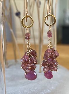 These gemstone 14K gold-filled hand wire-wrapped dangle cluster earrings feature pink sapphire briolette drops topped with cascading pink tourmaline rondelles. The gemstones hang from a delicate asymmetrical vermeil hoop and two hand wire wrapped pink tourmalines.  The earrings drop approximately 2 inches and are finished off with gold-filled French ear wires. About these Earrings: - Gemstones: Pink sapphire and pink tourmaline  -Metal: Gold (all 14K gold filled components except vermeil hoop) - Earring drop/length: approximately 2 inches - Lovely gift wrapped box included in all orders -Free domestic shipping! - Handmade in Connecticut  PLEASE NOTE, at this time, custom orders are not available  ♦️♦️♦️♦️♦️♦️♦️♦️ All the gemstones, metals, and findings I use are of the highest quality from Cluster Jewelry, Crafty Fox, Family Jewels, Long Dangle Earrings, Amazing Ideas, Earrings Drop, Cluster Earrings, Pink Tourmaline, Pink Sapphire