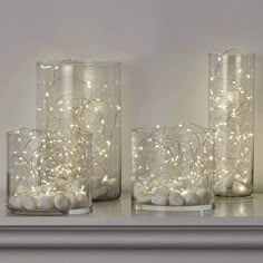 three glass vases with lights in them on a shelf