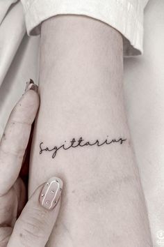 a woman's wrist tattoo with the word sytians on it