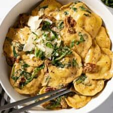 a white bowl filled with pasta and spinach