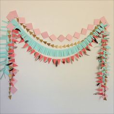 paper garlands are hanging on the wall with pink, blue and gold decorations around them