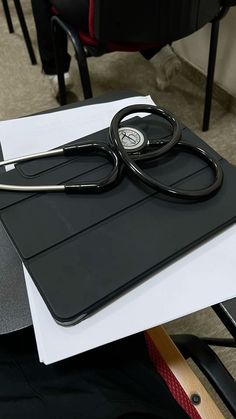 a black stethoscope sitting on top of a piece of paper next to a chair