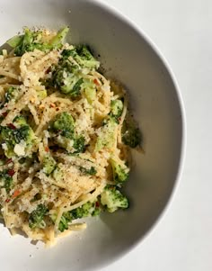 a bowl filled with pasta and broccoli on top of a white tablecloth