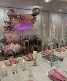 the table is set for a party with pink napkins, silver and white decorations