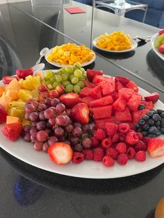 a plate full of fruit is sitting on a table with other plates and bowls in the background