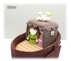 a crocheted dollhouse with two dolls in it's bed and one is wearing a green sweater