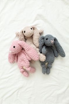 three crocheted stuffed animals laying next to each other on a white sheet,