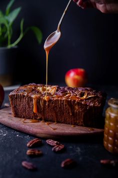 someone is drizzling caramel sauce on a piece of bread with apples in the background