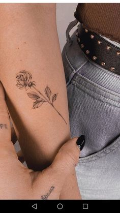 a woman's arm with a rose tattoo on it and another person holding her hand