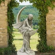 a statue of a woman sitting on top of a moon in front of an arch