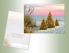 two greeting cards with christmas trees on the beach at sunset, one in gold and one in white