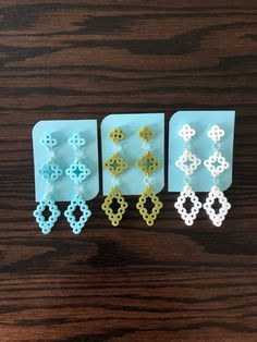 four pairs of beaded earrings sitting on top of a wooden table