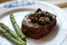 a steak with mushrooms and asparagus on a plate