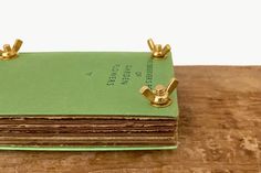 a green book with gold handles sitting on top of a wooden table