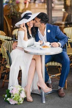 a man and woman sitting at a table in front of each other with hats on