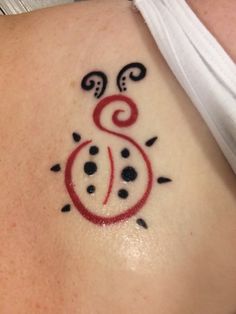 a small tattoo on the back of a woman's shoulder, with an image of a ladybug