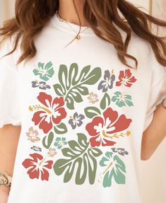 White Hibiscus Print T-shirt For Spring, Green Short Sleeve Top With Hibiscus Print, White Hawaiian Shirt With Floral Print, White Tropical Hawaiian Shirt With Hibiscus Print, Tropical Hawaiian Shirt With Hibiscus Print For Beach Season, Tropical Print Short Sleeve T-shirt, Cotton T-shirt With Tropical Print, Tropical White Hawaiian Shirt With Hibiscus Print, Green Hibiscus Print Vacation Top