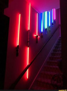 some lights that are on the side of a stair case in a room with red and blue lighting