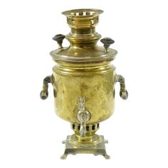 an antique brass urn with metal handles and knobs on the sides, set against a white background