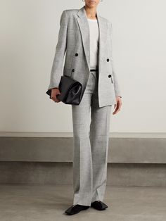 a woman in a gray suit holding a black purse